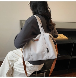 Detail of grey canvas tote bag with brown adjustable strap shown in a lifestyle setting