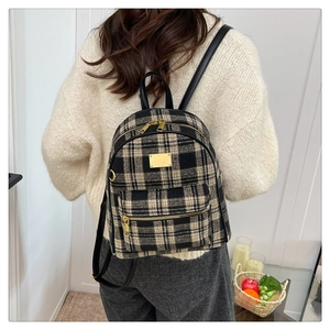Gros plan du sac à dos vintage à carreaux montrant la texture en tweed et le doré
