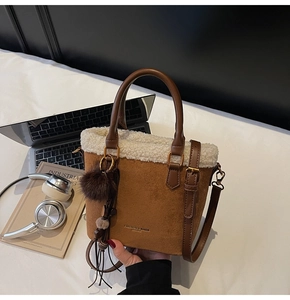 Détail du sac seau vintage en daim marron avec bordure en peau lainée et pompon en peluche
