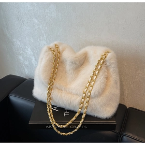 Détail du sac à bandoulière en fausse fourrure pelucheuse avec chaîne dorée sur un livre