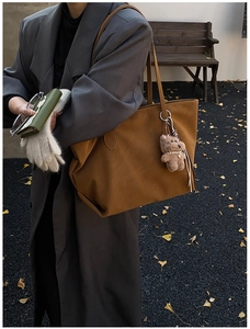 Detail view of a vintage large-capacity tote bag with a plush bear charm on a wool coat