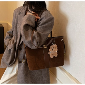 Deep brown suede tote bag with leather strap and cute bear charm shown on a model