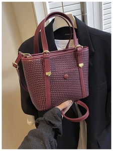 Dettaglio borsa shopper intrecciata bordeaux con fibbie dorate e tracolla regolabile