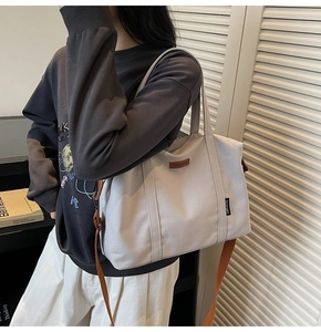 Detailed view of cream canvas tote bag with brown adjustable strap and leather logo label