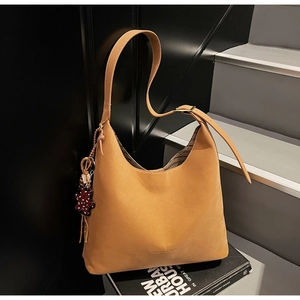 Close-up of hobo bag in camel suede with adjustable strap and cute bear charm