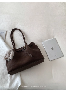 Detailed view of brown matte leather tote bag with shoulder strap and plush bunny charm