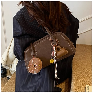 Detail of vintage brown suede shoulder bag with decorative charms on model in navy suit