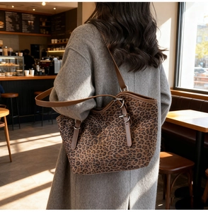 Dettaglio borsa tote leopardata con cinturini in pelle marrone e fibbie argentate