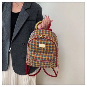 Détail d'un sac à dos en tweed multicolore avec poignée en cuir rouge et finitions dorées