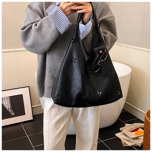 Détail du sac cabas noir avec motifs floraux découpés au laser et texture cuir lisse