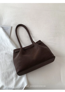 Flat lay of minimalist dark brown matte tote bag on white fabric with retro vibes