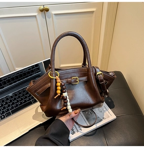 Detailed shot of dark coffee leather handbag with decorative wooden beads and metal buckle