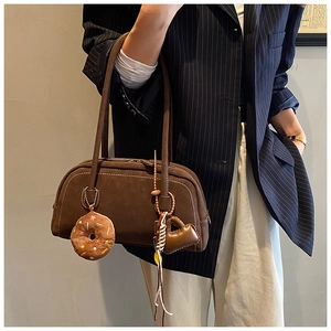 Brown suede Boston bag detail with contrast stitching and decorative charms in a lifestyle shot