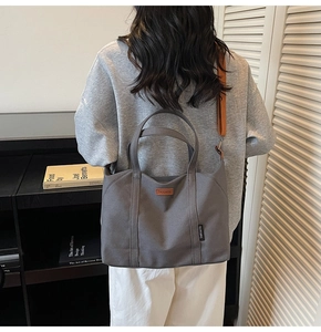 Detail of grey canvas tote bag with brown leather tag and premium fabric handles
