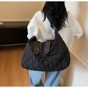 Detail view of black quilted puffer tote bag with diamond pattern and embroidered accents