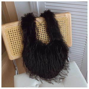 Détail du sac à main cœur en fausse fourrure noire accroché à une chaise en osier