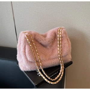 Détail du sac à bandoulière en peluche rose avec une chaîne dorée entrelacée de cuir rose