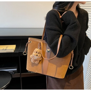 Brown suede tote bag with metal ring detail and cute plush bear charm for daily commute