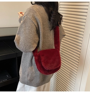 Detail view of the wine red faux fur shoulder bag worn by model in a stylish indoor setting