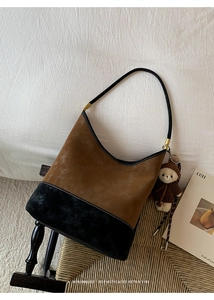 Dettaglio borsa hobo retrò in pelle scamosciata marrone con tracolla nera e orsetto