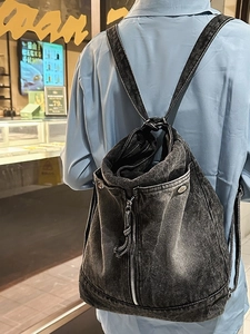 Retro black washed denim backpack with metal zipper and rivets on a female model