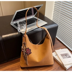 Brown leather Hobo bucket bag with a cute bear charm on a stylish office desk setup