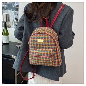 Détail du sac à dos en tweed à carreaux avec lanières rouges et plaque dorée