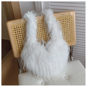 Gros plan du sac à main en plumes blanches suspendu sur une chaise en bois clair