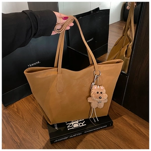 Detailed view of a brown faux leather tote bag with a cute plush dog pendant accessory