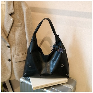 Détail du sac hobo noir avec fleurs découpées au laser sur une valise argentée élégante