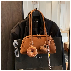 Detailed macro view of a brown suede Boston bag with heart and donut charms