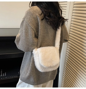 Detail view of the soft faux fur crossbody bag in creamy white on a female model