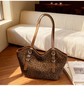 Dettaglio della borsa tote scamosciata leopardata con tracolle marroni e fibbie