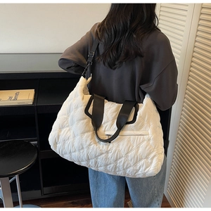 Detail showing white quilted puffer tote bag with floral embroidery and black handles