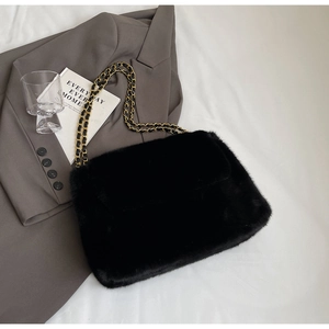 Détail du sac à bandoulière en fausse fourrure noire avec chaîne dorée et texture douce