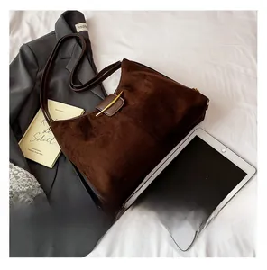 Detail of dark brown suede shoulder bag with golden metal buckle in a lifestyle setting