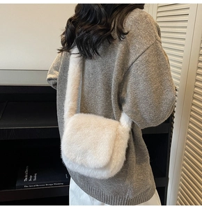 Detailed view of a white fluffy plush crossbody bag worn over a beige knit sweater
