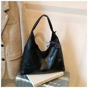 Détail de motifs floraux découpés au laser sur un grand sac hobo en cuir PU noir