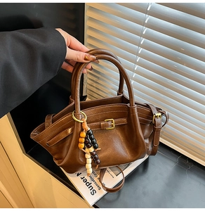 Detail of vintage brown trapezoid handbag with beaded charm and gold hardware