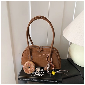 Detail of dark brown vintage faux leather underarm bag with cute hanging charms on books