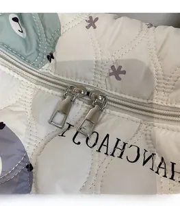 Dettaglio della doppia cerniera in metallo liscio su una borsa trapuntata con stampe carine