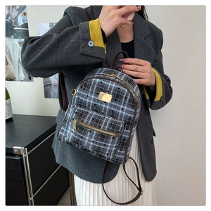 Détail du sac à dos à carreaux bleus avec motifs d'étoiles et bretelles en cuir marron