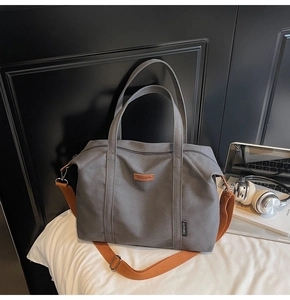Detail of the large grey canvas tote bag with adjustable brown strap and top zipper