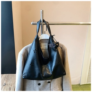 Détail du sac cabas noir découpé au laser avec accessoire sur une veste beige