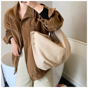 Detailed shot of large canvas tote bag with metal rivets and brown leather strap