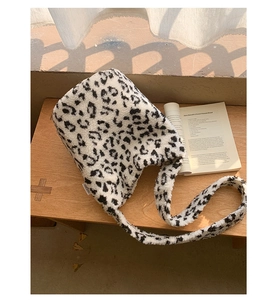 Détail d'un sac seau en peluche à motif léopard noir et blanc sur un banc