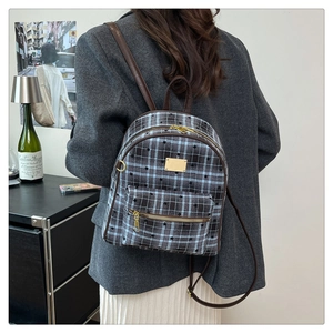 Détail d'un sac à dos vintage à carreaux avec motifs d'étoiles et lanières en cuir brun