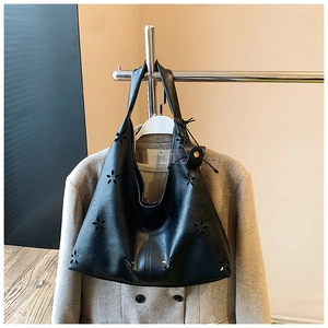 Détail du sac cabas noir ajouré au laser porté avec un élégant manteau en laine