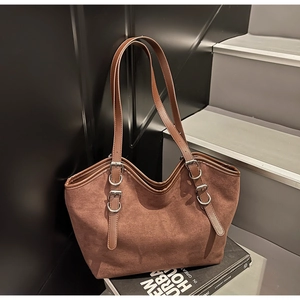 Dettaglio borsa tote in pelle scamosciata marrone con fibbie metalliche e finiture in pelle