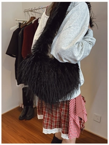 Détail d'un sac bandoulière en fausse fourrure noire avec une large bandoulière